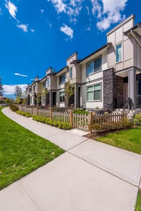 Modern multifamily townhomes with stone accents along a landscaped sidewalk